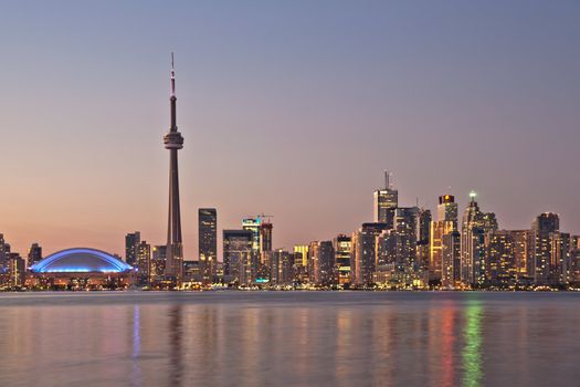 The landmark Toronto downtown view from the center island. Scenic view of the CN Tower illuminated by the iconic downtown skyline of skyscrapers and high rise condominiums reflecting in Lake Ontario 