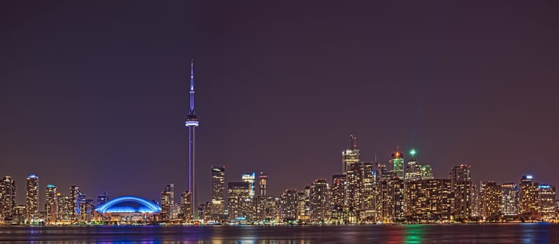 The landmark Toronto downtown view from the center island. Scenic view of the CN Tower illuminated by the iconic downtown skyline of skyscrapers and high rise condominiums reflecting in Lake Ontario 