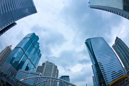 Fish eye view of Skyscrapers with Reflections under dark clouds