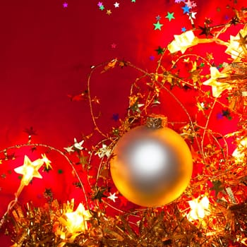 Christmas bauble with star-shaped lights and tinsel on red background