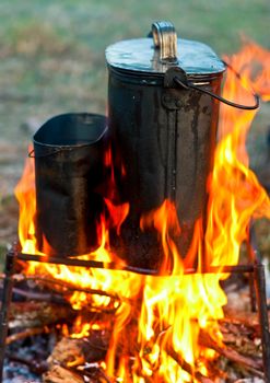 Two camping kettles over burning campfire