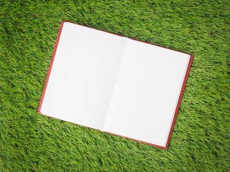 open blank book on artificial green grass