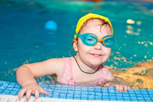 Little girl wearing goggles in a swimming pool