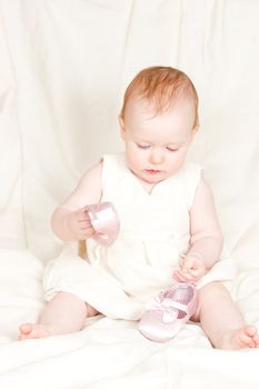 Little baby girl playing with shoes