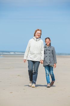 Beautiful girl and her grandmother walking on the beach. Holland