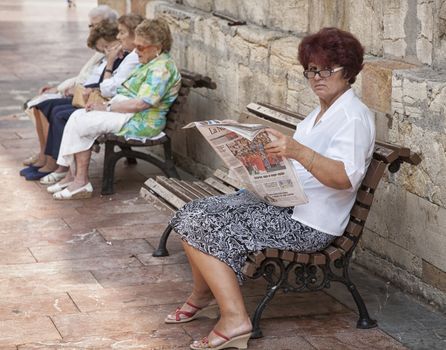 THE DAILY NEWS, OVIEDO, SPAIN - SEPTEMBER 17: Senior female sitting outdoor enjoying her newspaper in the shade - Oviedo, Spain september 17, 2012.
