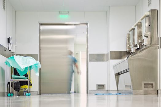 Blurred figure in medical uniform exiting corridor