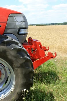 The front of a tractor for farming on a background field of wheat