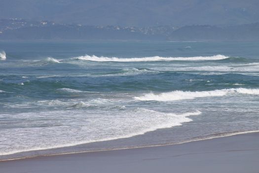 panoramic views of the ocean with its beach and waves over a blue sky