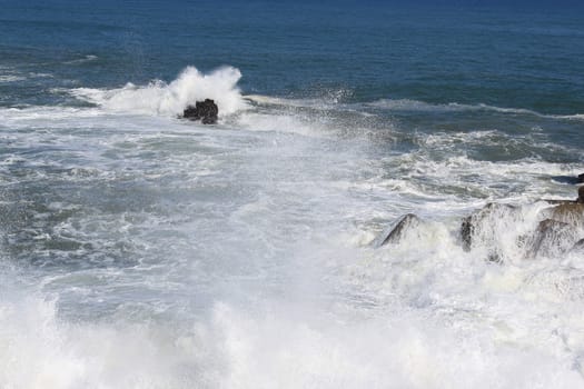 several waves at high tide break on the rocks by the sea