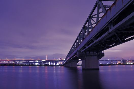 huge metallic railroad bridge over Arakawa river waters in Tokyo, Japan