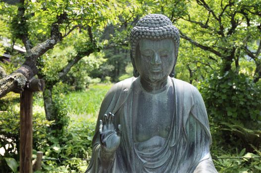 japanese Buddha statue in zen garden environment in Kamakura, Japan; focus on face and hand