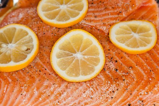 Raw salmon with orange slices in the baking pan ready for cooking.