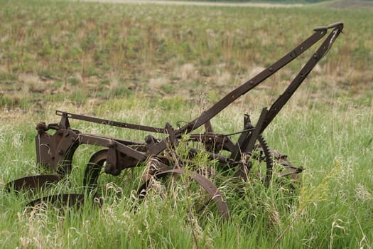 An antique plow abandoned in a field in spring in Winnipeg, Manitoba, Canada