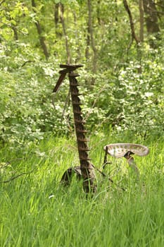 An antique, horse drawn grass cutter abandoned in a farmers field in spring in Winnipeg, Manitoba, Canada