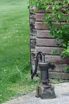 An antique water pump on a concrete cistern on a farmyard in spring in Altona, Manitoba, Canada