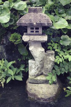 small stone lantern among fresh zen garden plants