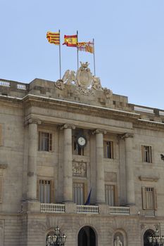 main building of Catalonia Government in Barcelona on Placa Sant Jaume with Catalan,Spanish and Barcelona flags on the top