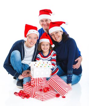 Portrait of friendly family in Santa's hat with gift box and gingerbread house, isolated on white