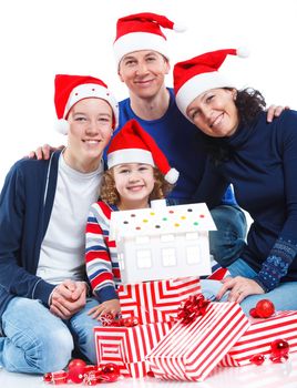 Portrait of friendly family in Santa's hat with gift box and gingerbread house, isolated on white