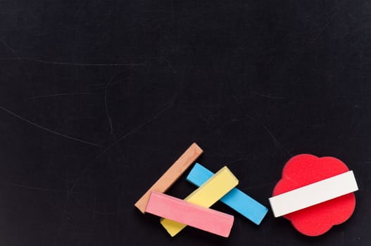 Empty blank black chalkboard with red sponge and colorful chalk