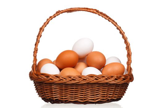 Brown and white eggs in the wicker basket over white background