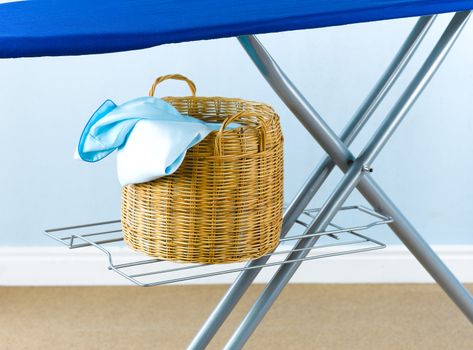 The rattan basket beneath the laundry board for keeping the wrinkle cloths