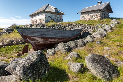  Old boat and stone houses on the shore. Bolshoi Zayatsky Island, Solovetsky Islands, The White Sea, Karelia, Russia.