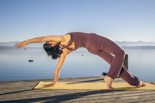 An image of a pretty woman doing yoga at the lake