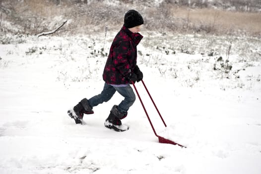 Young boy shoveling away snow with a shovel