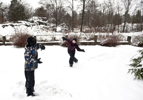 Children playing outdoors at winter time throwing snow balls at each other