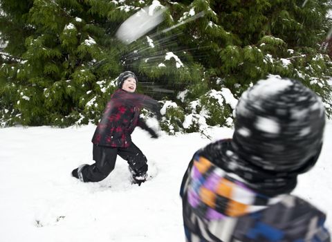 Children playing outdoors at wintertime throwing snowballs at each other