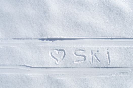 heart symbol and ski word handwritten between ski tracks on fresh snow