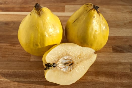 Three and half organic quinces on wooden plate
