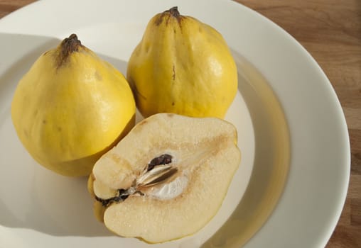 Three and half organic quinces on white plate