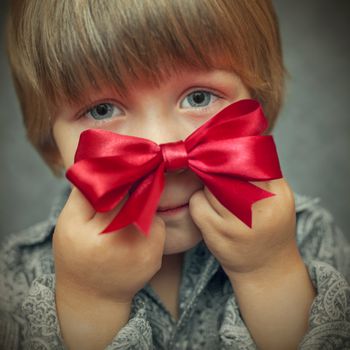 little boy with a red bow in hand