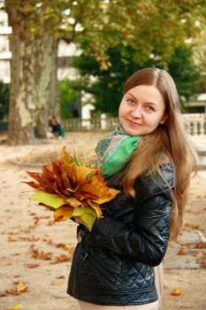 beautiful girl portrait while hoilding leaf bouquet in park 