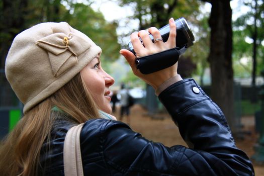 beautiful girl holds camera for filming on street