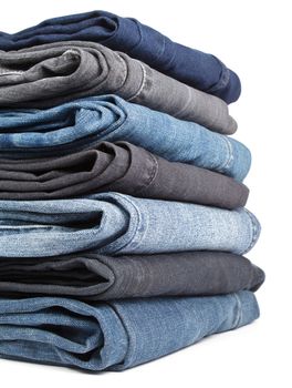 Stack of blue and black Jeans on white background