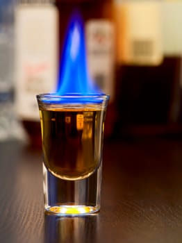 Burning cocktail in shot glass on a table, shallow focus
