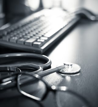 Stethoscope on a table with keyboard and glasses, very shallow DOF