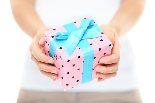 Hands holding a decorative Xmas gift with pretty pink polka dot paper tied with a turquoise ribbon and bow for your Christmas greeting