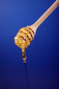 close up of a  honey dipper over blue