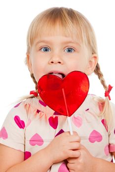 Cute little girl licking big red heart shaped lolly pop candy