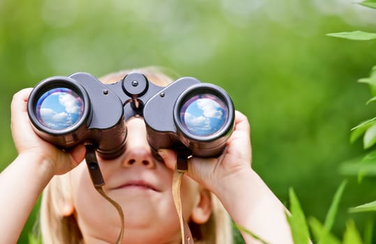 Little girl looking through binoculars outdoors