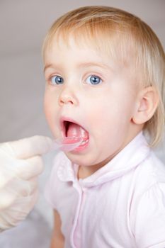 Doctor giving a spoon of syrup to cute little girl