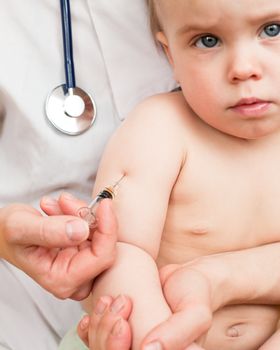 Doctor giving a child an intramuscular injection in arm, shallow DOF