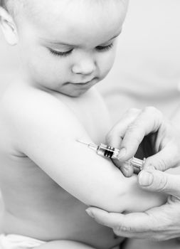 Doctor giving a child an intramuscular injection in arm, shallow DOF