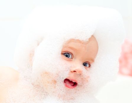 Happy little baby girl bathing in soapsuds
