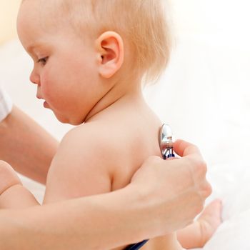 Pediatrician examining little baby girl with stethoscope